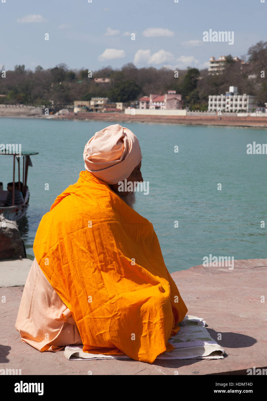 Holy man sitting on ferry pier waiting for boat,Rishikesh, India Stock Photo