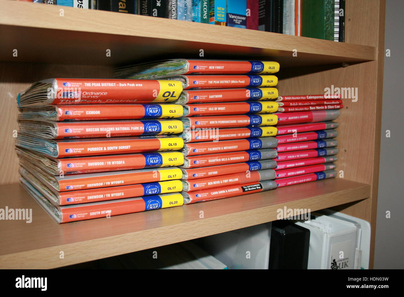 A collection of Ordnance Survey outdoor leisure maps lined up on a bookshelf Stock Photo