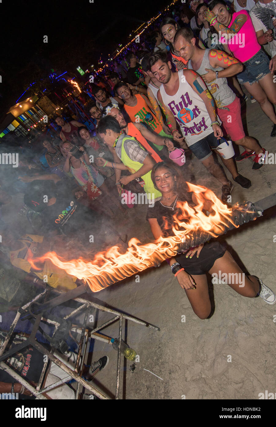 A party goer joins in a limbo dance under a burning pole at a  Full Moon party on Sunrise beach Haad Rin on the island of Kho Phag Nang Thailand Stock Photo