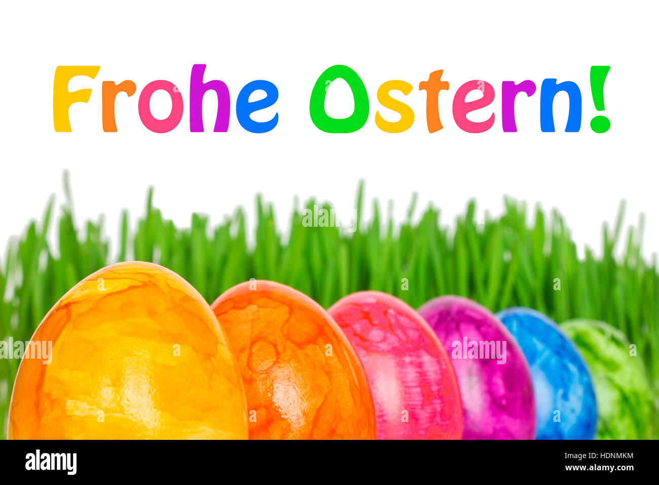 Template Happy Easter in german, Frohe Ostern, with 6 colorful Easter Eggs in front of green grass, bright rainbow colors Stock Photo