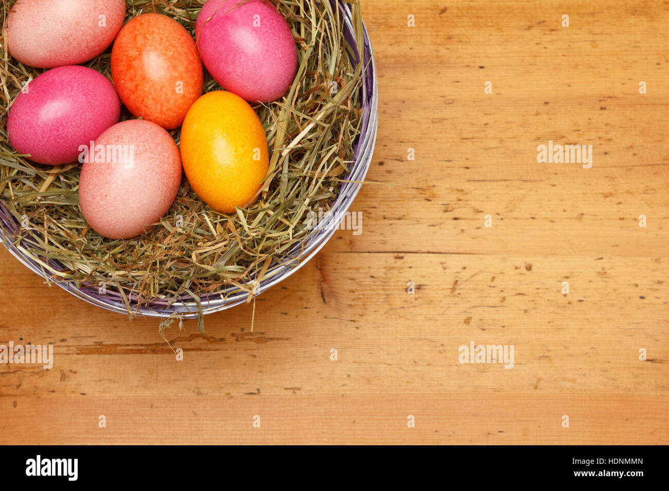 Six Easter Eggs in soft, natural colors in a basket with straw on vintage wood, copy or text space, retro background template Stock Photo