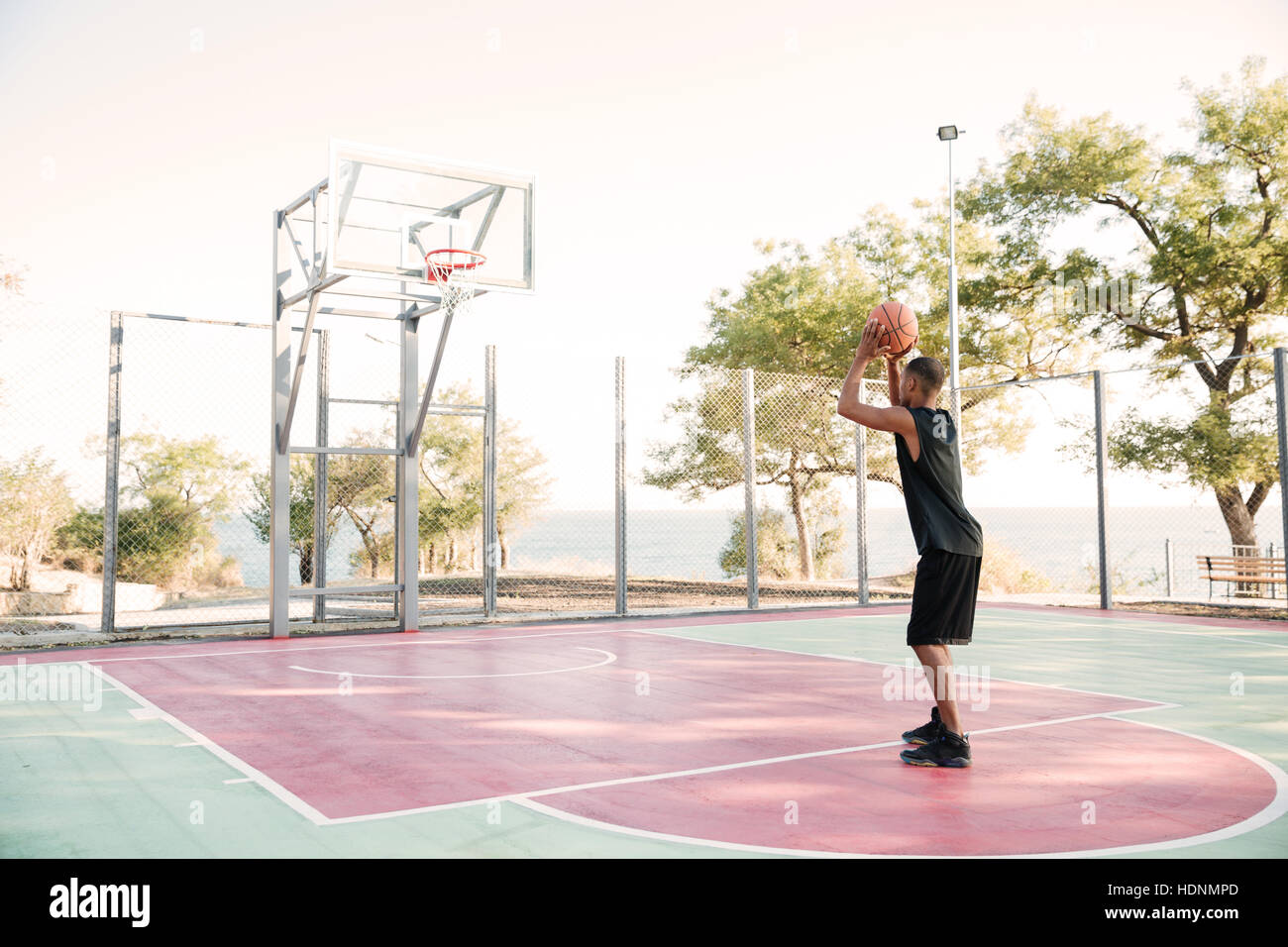 Image of african basketball player in the street with ball. Looking at basketball hoop. Stock Photo