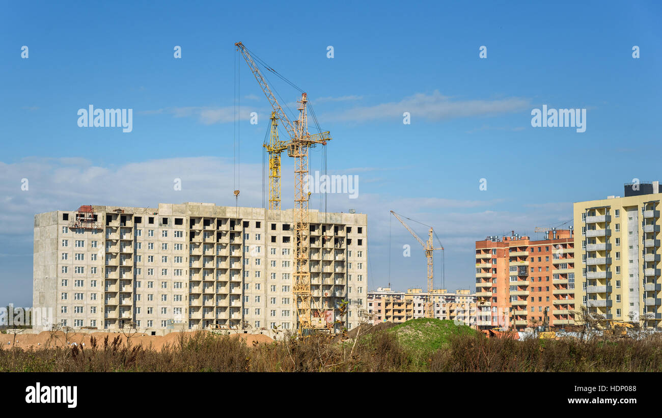 construction of apartment buildings and a crane on blue sky background ...