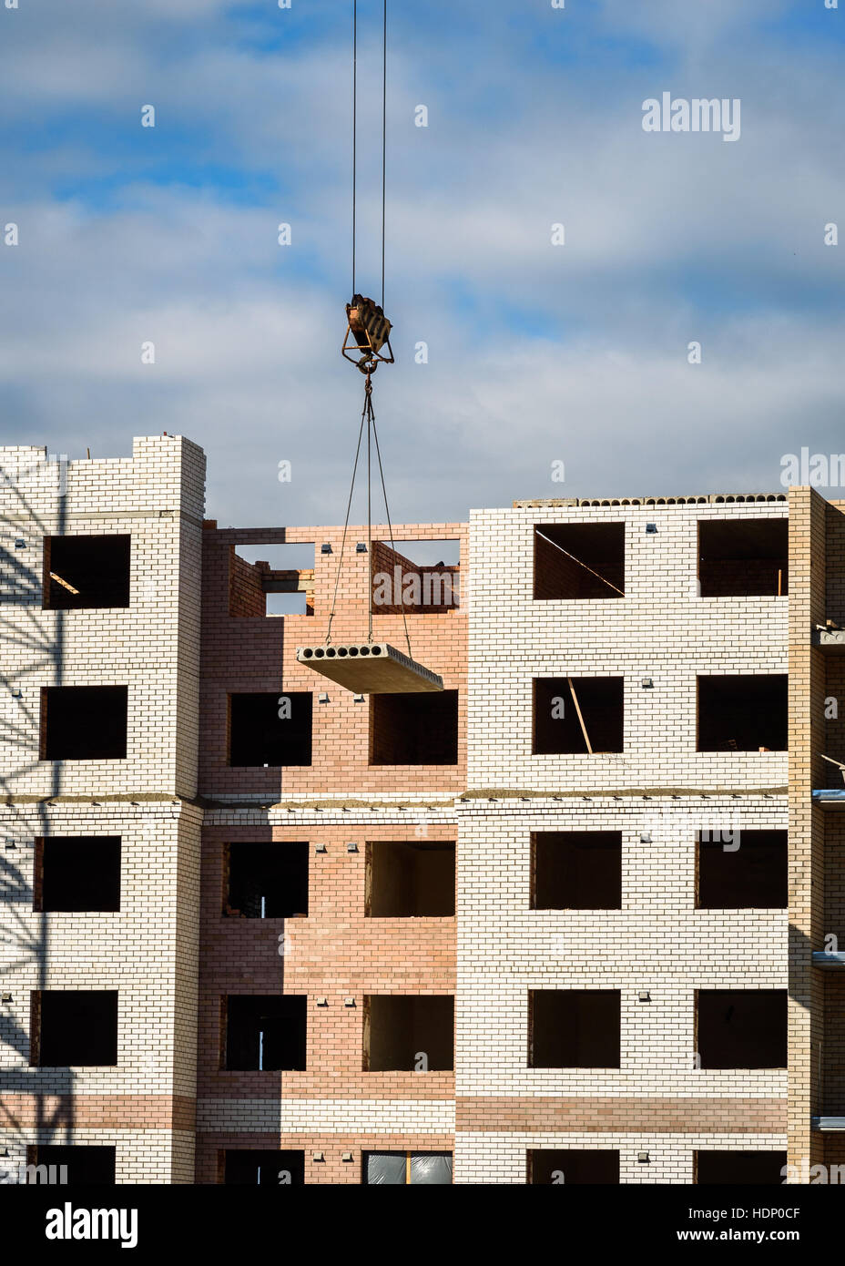 Crane lifting cement block on the background of building under construction Stock Photo