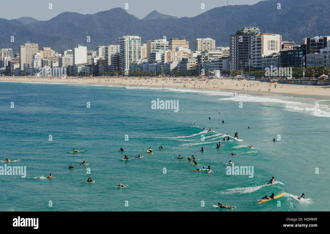 Beachgoers relax on the Arpoador end of Ipanema Beach with colorful umbrellas against a city skyline with Two Brothers Mountain Stock Photo