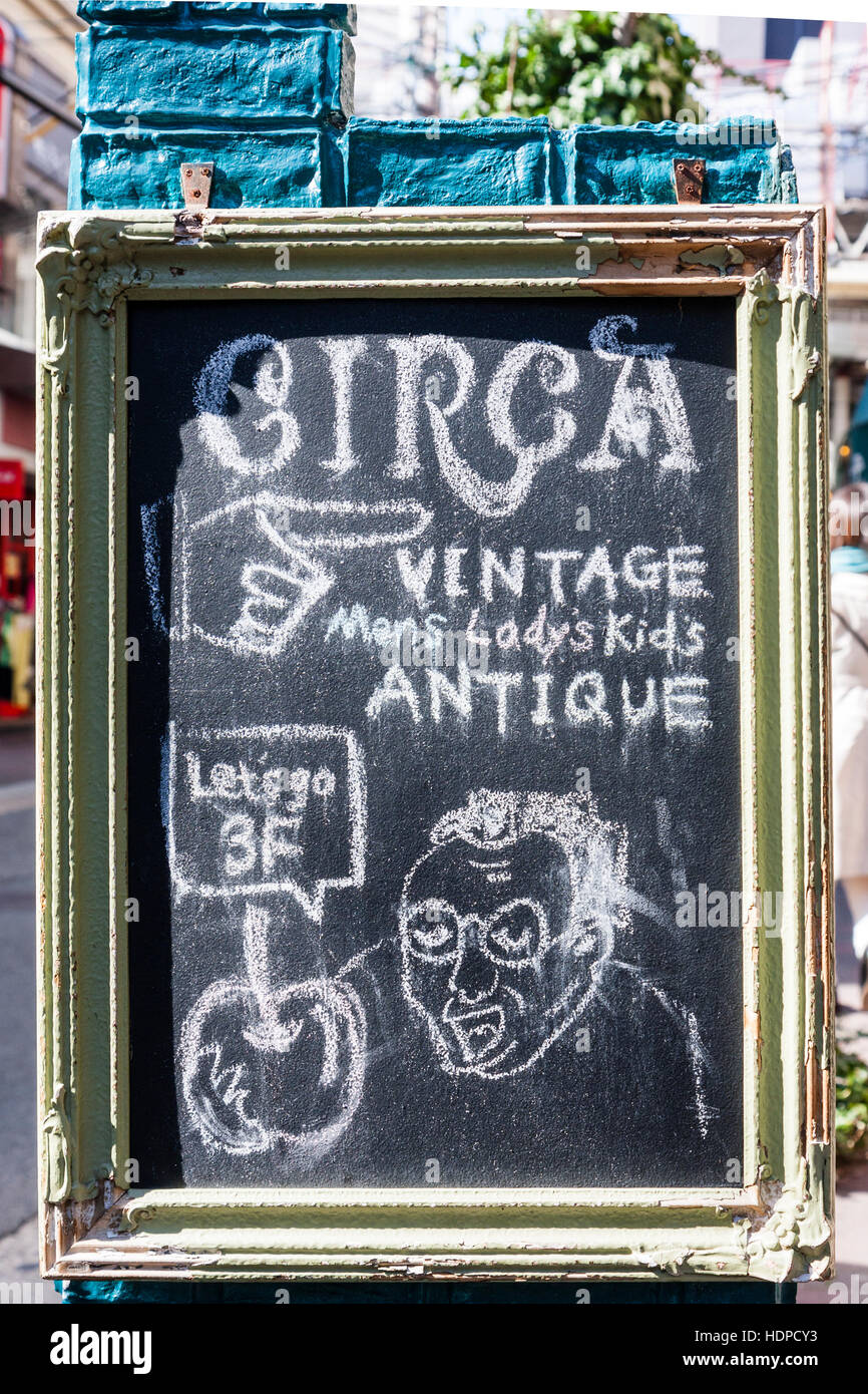 Japan, Kobe, Nankinmachi, Chinatown. Chalk board sign on pavement in English, Circa', Vintage antiques on third floor with cartoon of man holding sign. Stock Photo