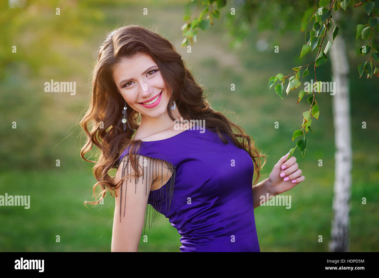 young woman in purple dress walking in summer Park Stock Photo