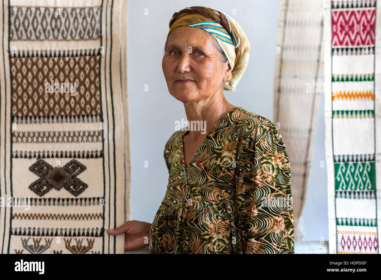 Local woman holding the rugs she makes in Nukus, Uzbekistan Stock Photo