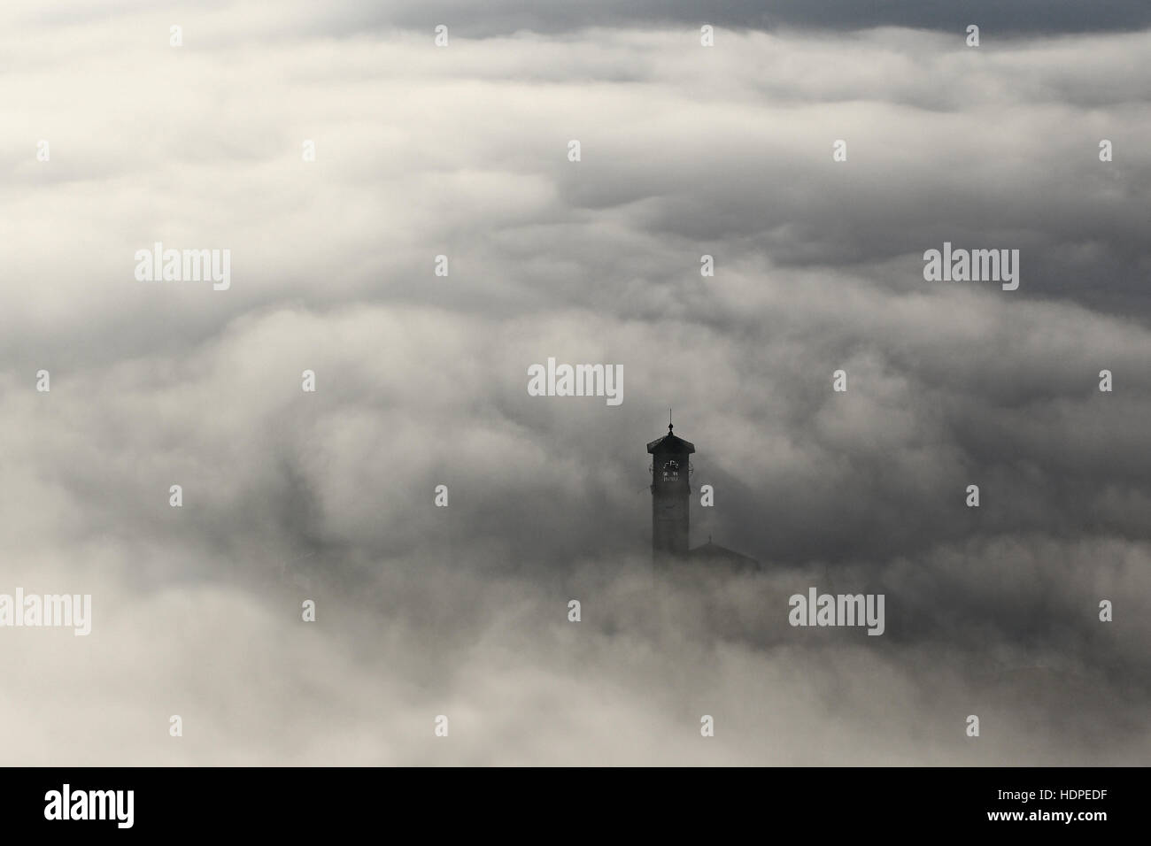 Aerial view of church steeple peeking out of winter fog background Stock Photo