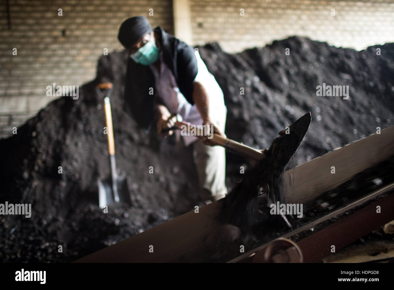 Workers shovel coal to power a boiler at a cotton dye-works in Tamil Nadu, southern India. Stock Photo