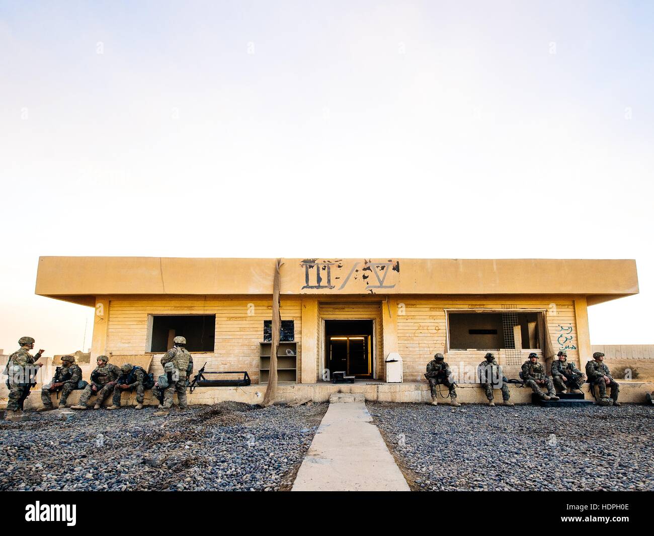 U.S. soldiers rest under the overhang of an abandoned building at the Qayyarah West Airfield November 19, 2016 in Qayyarah, Mosul district, Iraq. Stock Photo