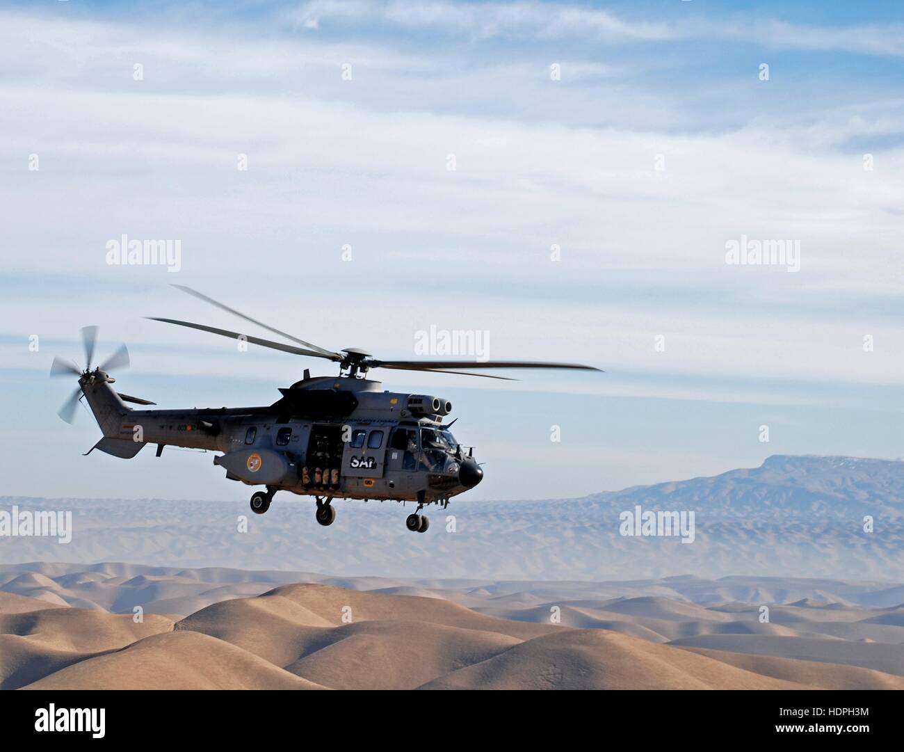 A Spanish Air Force Eurocopter AS332 Super Puma utility helicopter flies over the desert sand dunes December 24, 2008 in Herat, Afghanistan. Stock Photo