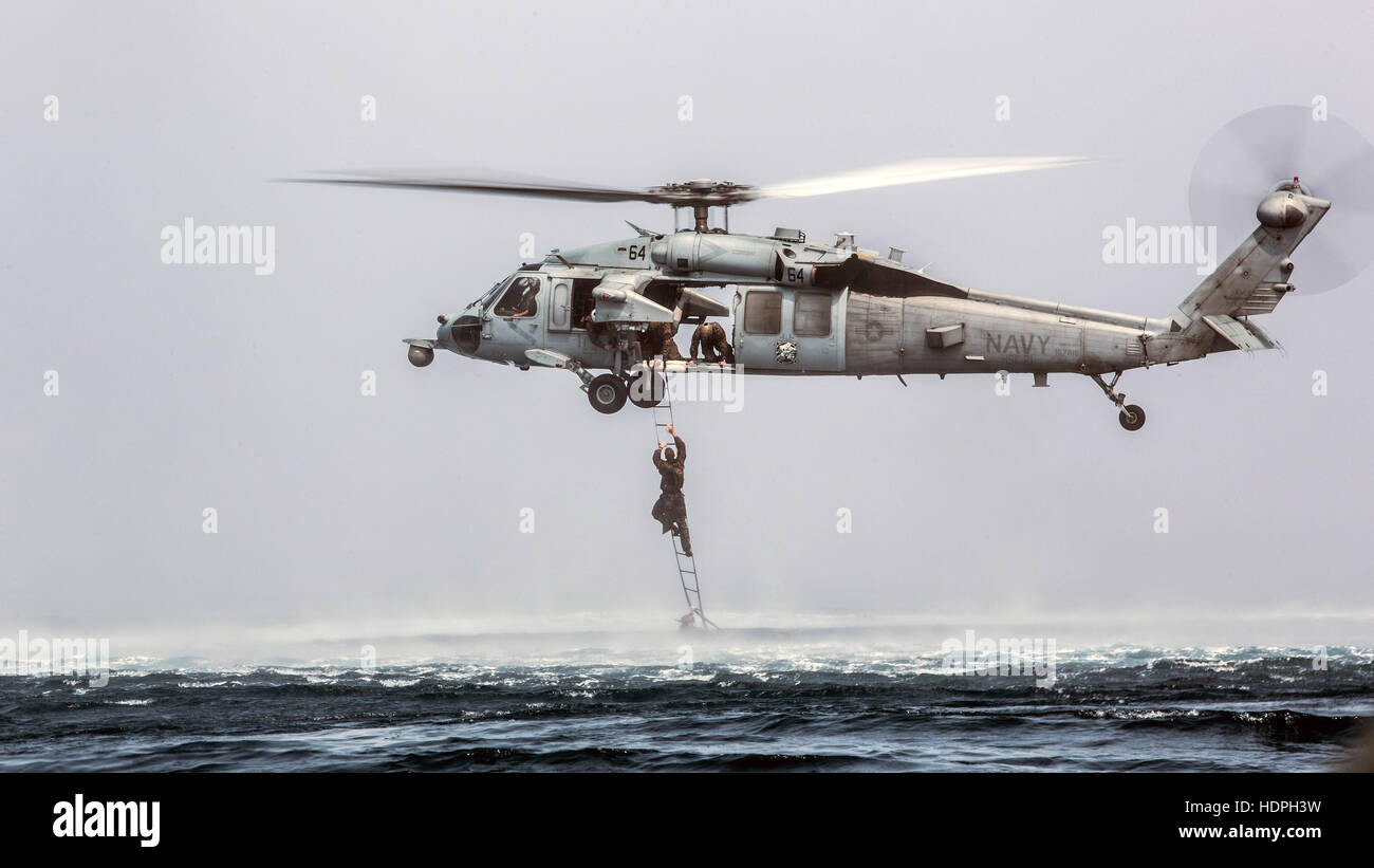 A U.S. Marine special operations soldier climbs a caving ladder on a Sikorsky MH-60 Seahawk helicopter during a helocast training evolution November 28, 2016 in the Indian Ocean. Stock Photo