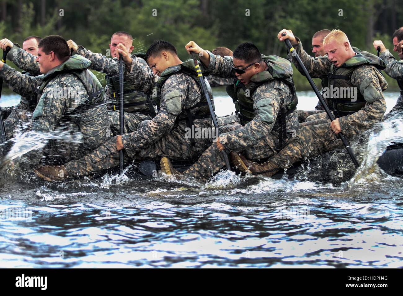 U.S. paratrooper soldiers paddle an inflatable Zodiac boat across Mott Lake during water teamwork training at Fort Bragg July 30, 2015 near Silver City, North Carolina. Stock Photo