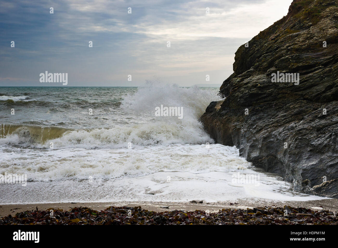 Thunderous wave crashing against the rocks in an isolated alcove along the South West Coastal Path, Cornwall, UK Stock Photo