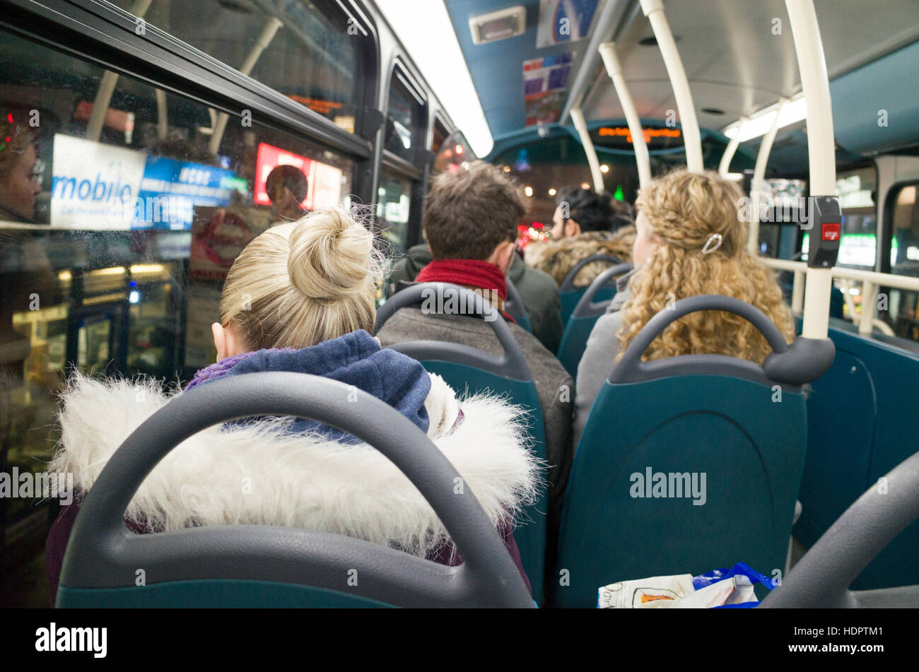Woman passenger travelling alone on the top deck of a night bus, London, England, UK Stock Photo