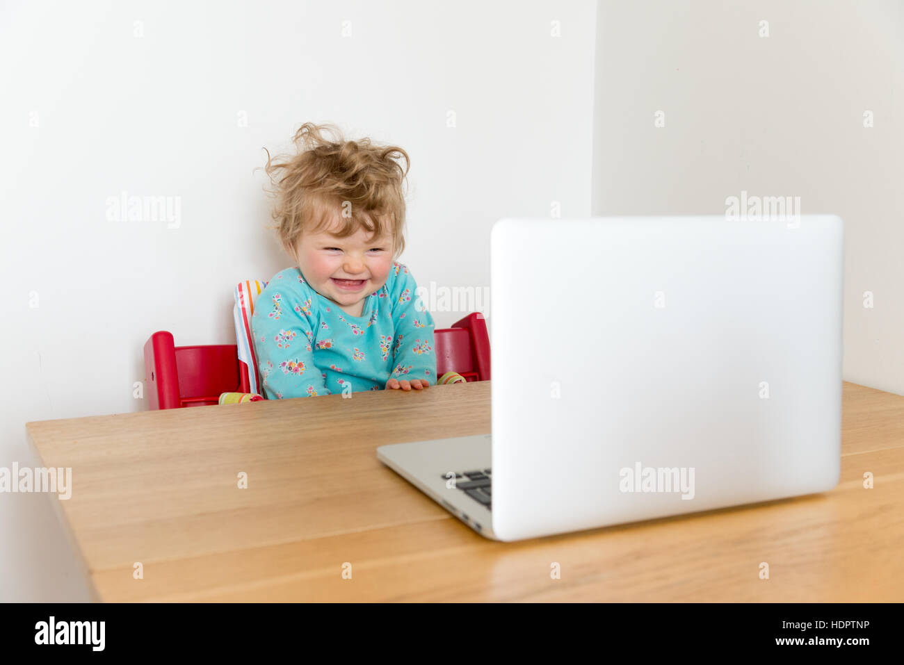 One year baby girl watching screen of laptop computer, England, UK Stock Photo