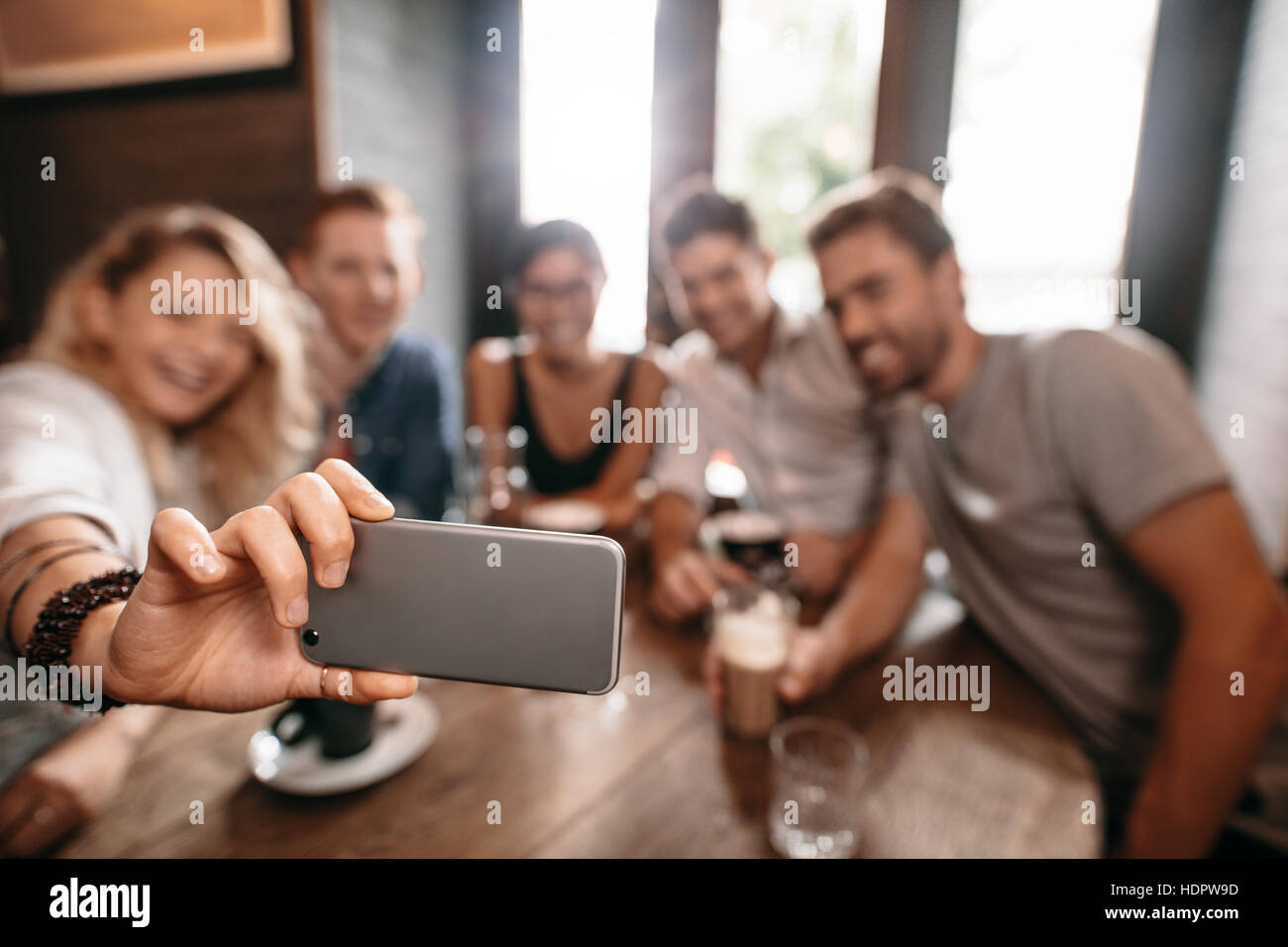 Group of young people taking a selfie at cafe. Young friends at restaurant taking self portrait. Stock Photo