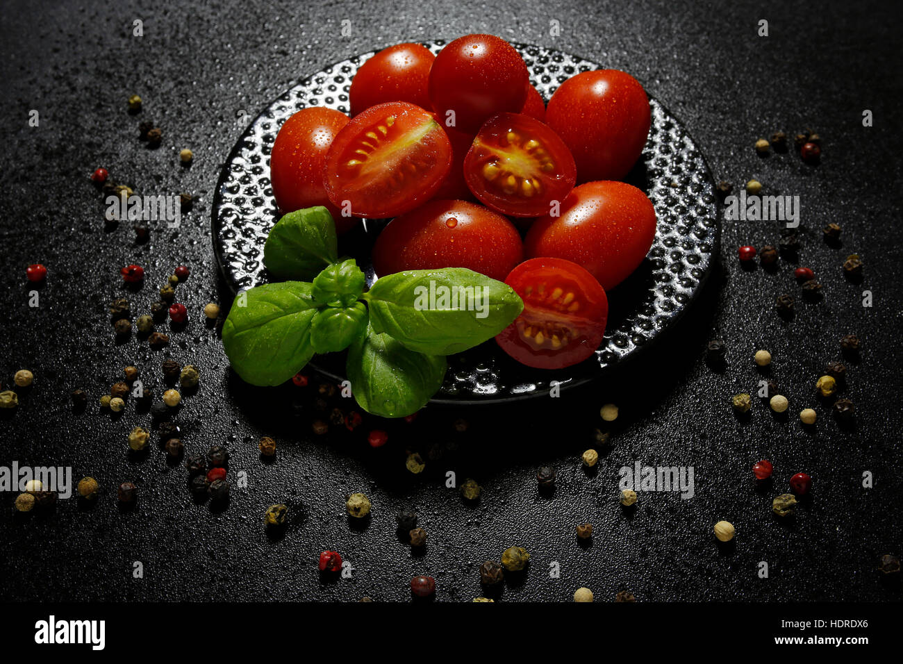 cherry tomatoes with basil leaves on black shiny background Stock Photo ...