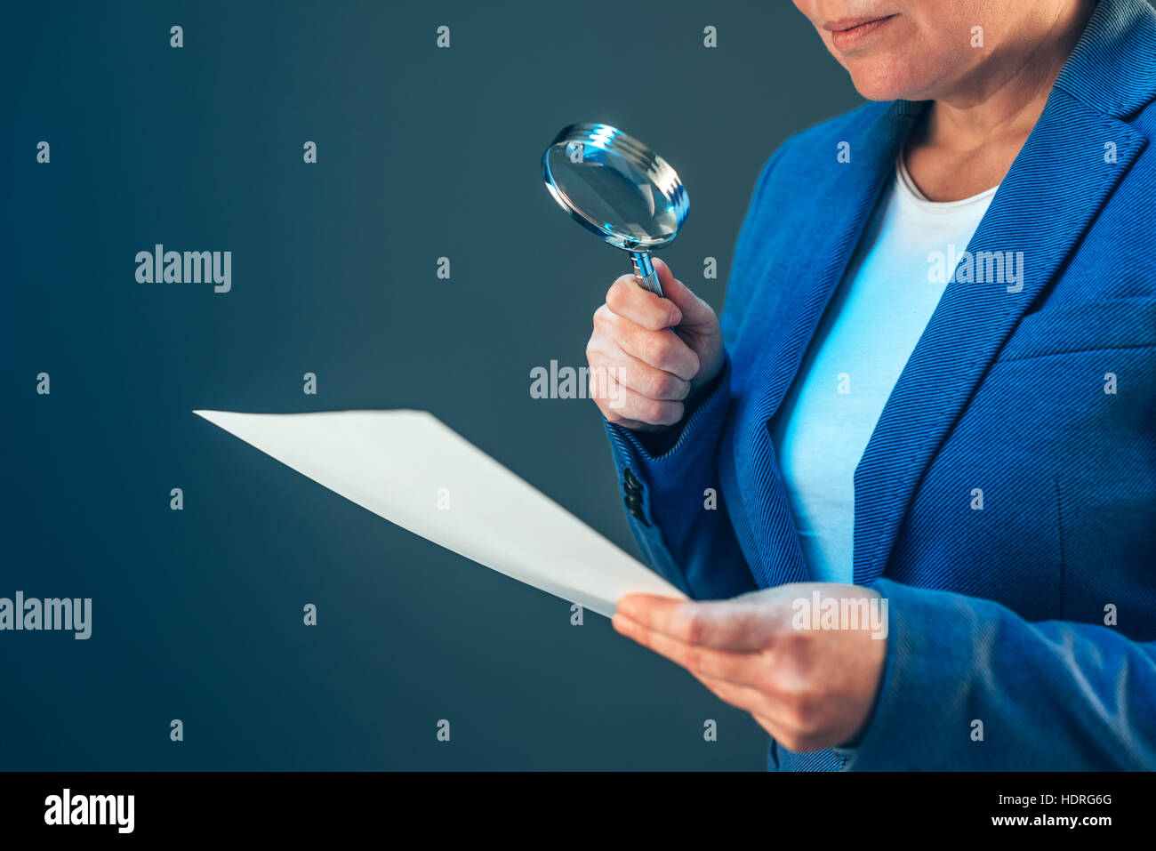 Female tax inspector looking at corporate financial documents with magnifying glass Stock Photo