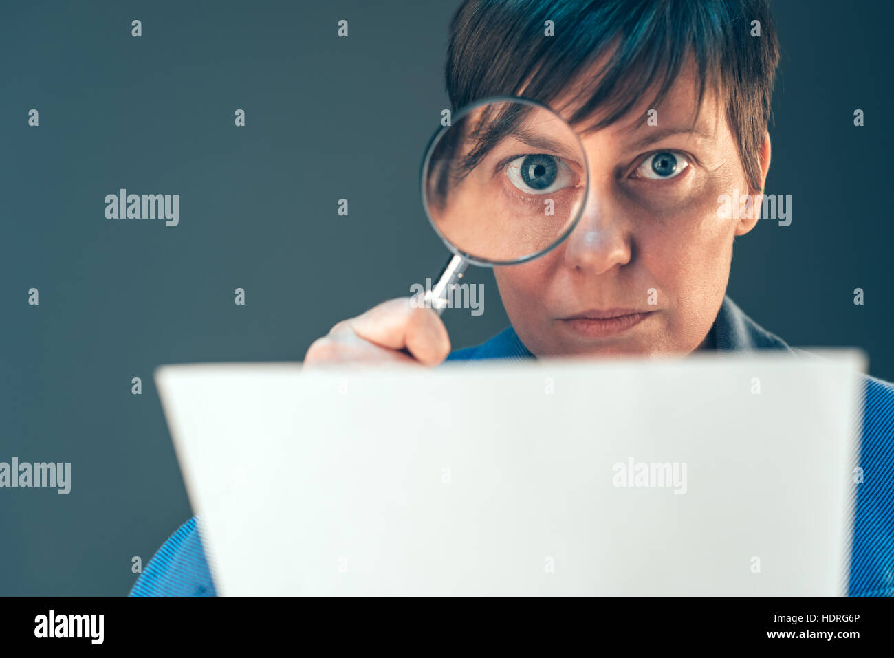 Female tax inspector looking at corporate financial documents with magnifying glass Stock Photo