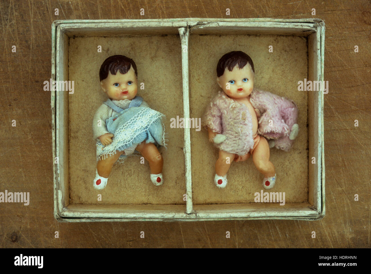 Cardboard box with two compartments each containing vintage doll one dressed in blue and one in pink Stock Photo