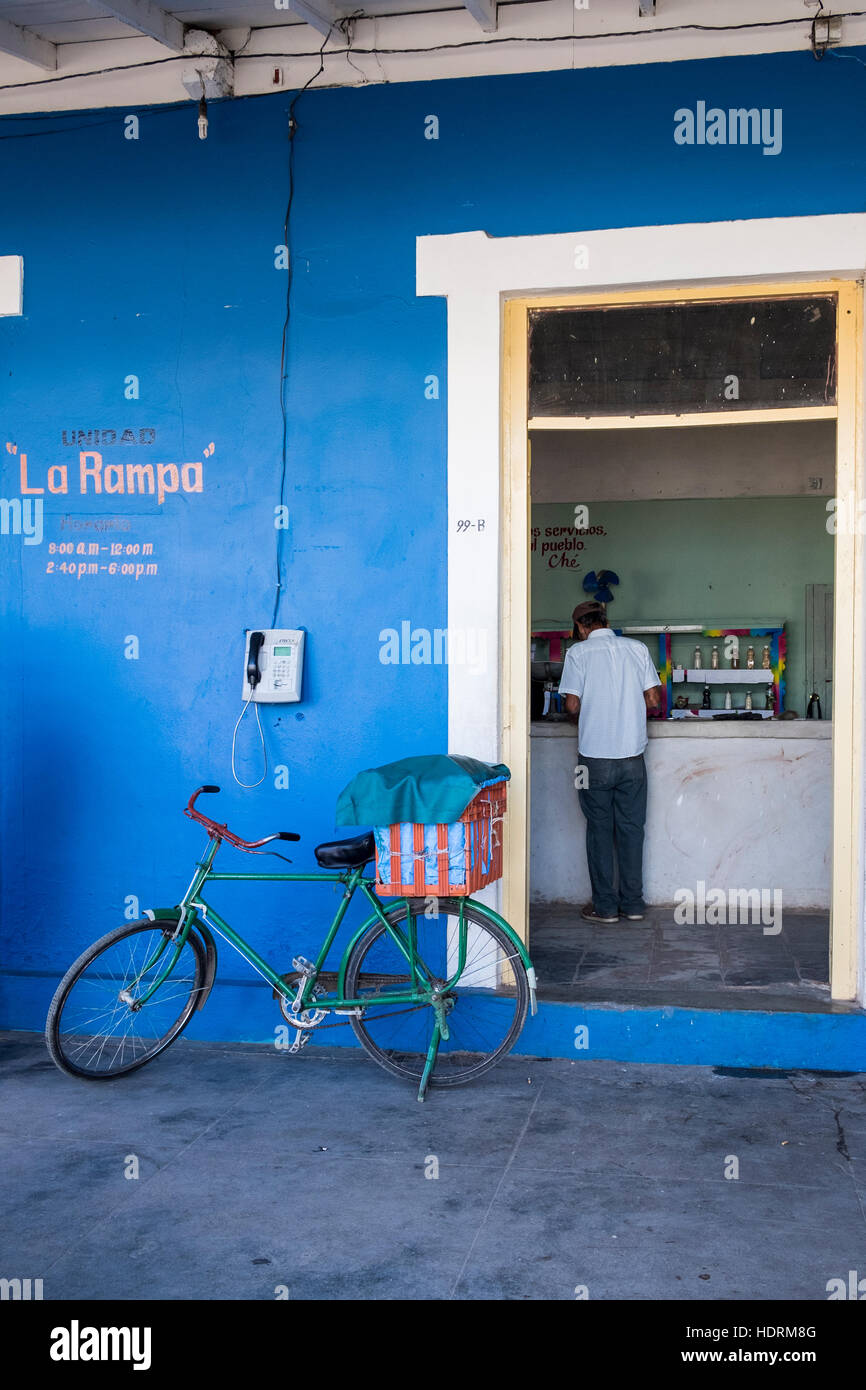Ration shop in Vinales, man at counter and bicycle leaning against wall outside, Cuba Stock Photo