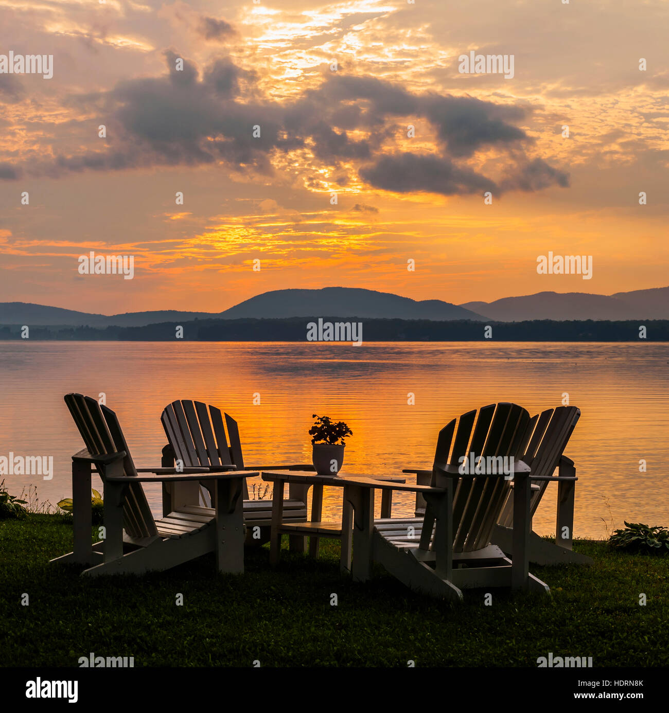 Sunset on lake with silhouetted chairs on wharf; Knowlton, Quebec, Canada Stock Photo