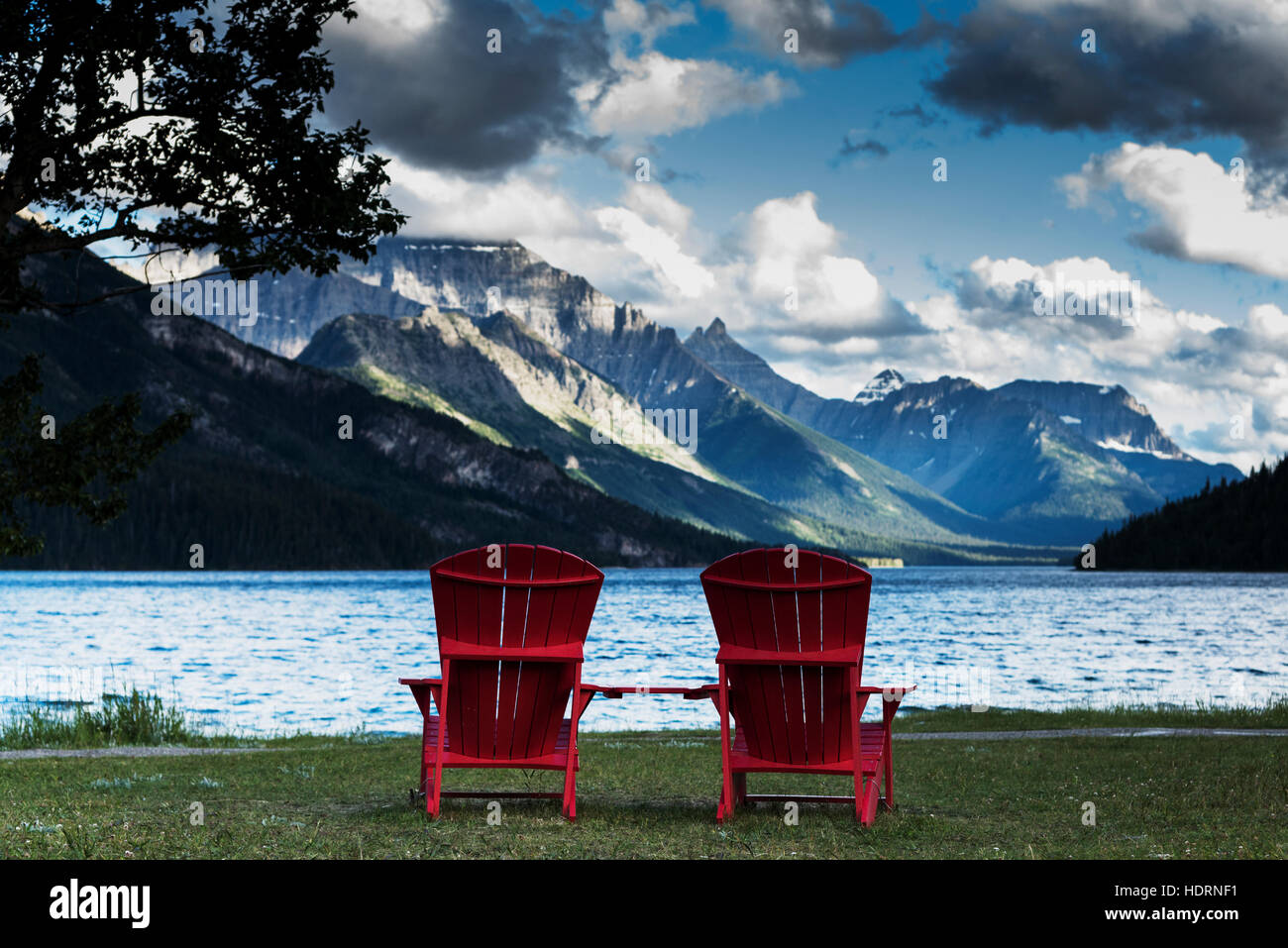 Two Red Adirondack Chairs Sit Facing The Lake And Rocky