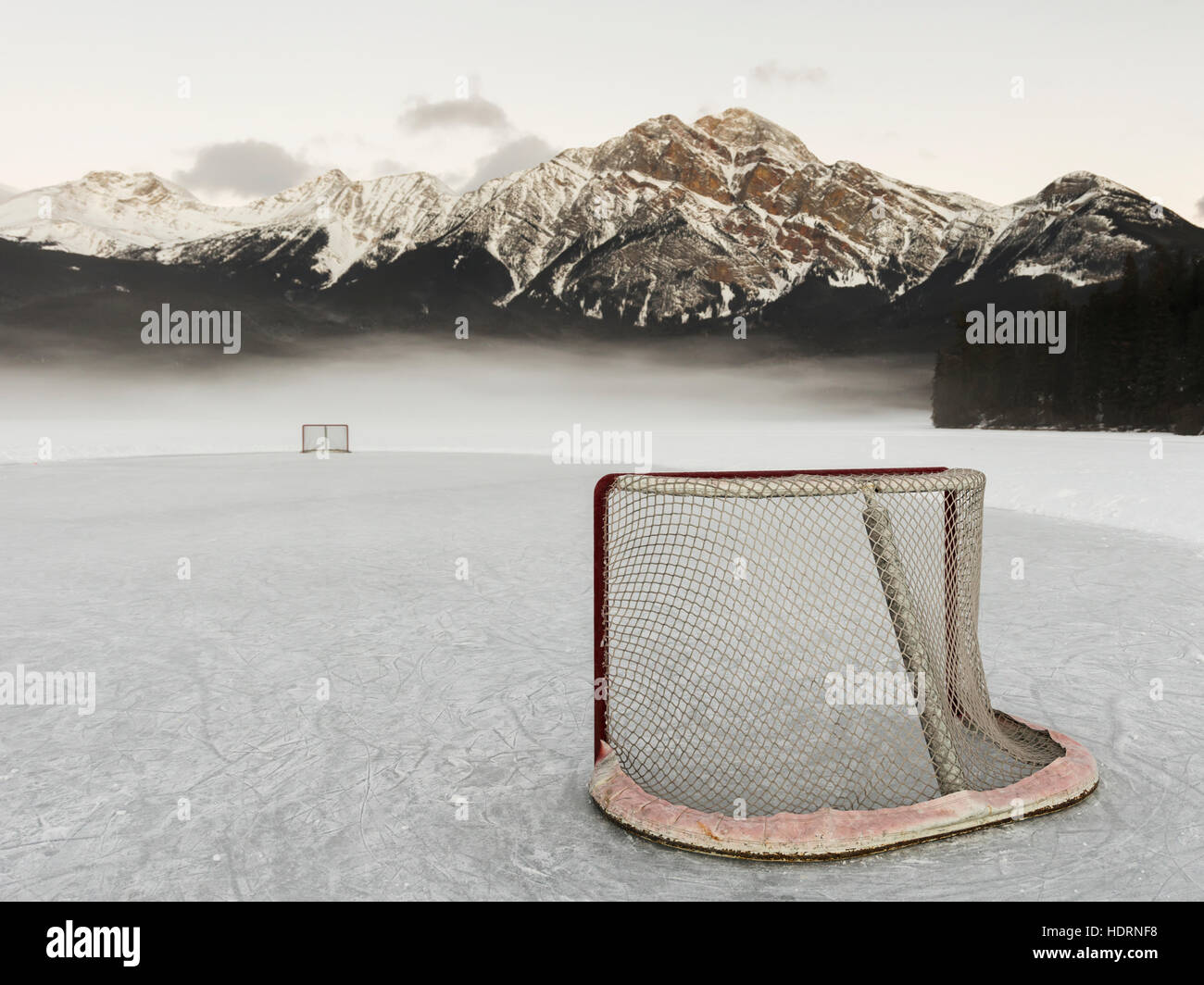 A hockey net on frozen Pyramid lake with the rugged Canadian Rockies mountain range in the background, Jasper National Park; Alberta, Canada Stock Photo