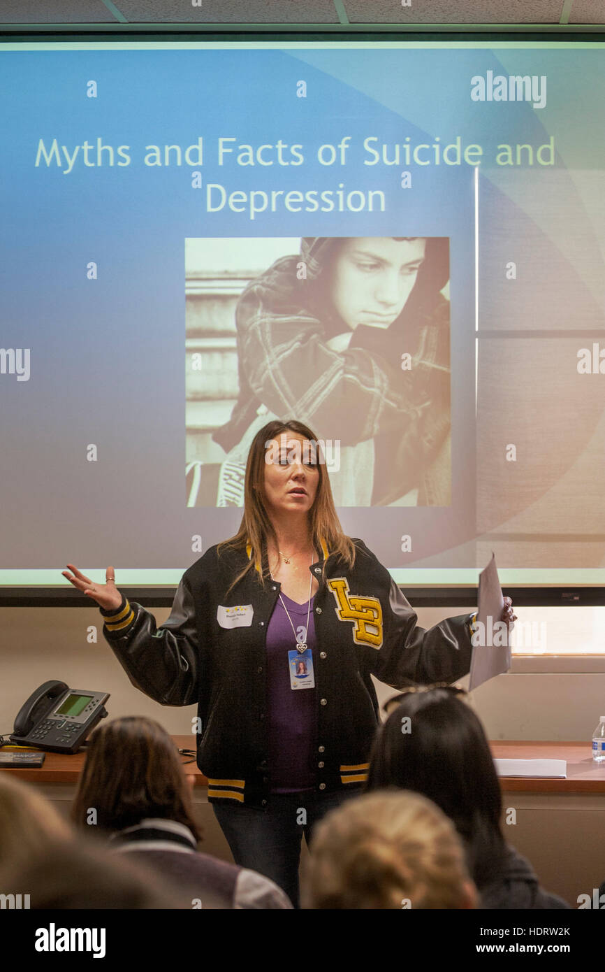 A school counselor lectures on suicide at a meeting with local teachers in a community open house at school district headquarters in San Juan Capistrano, CA. Note school jacket and visual aid. Stock Photo
