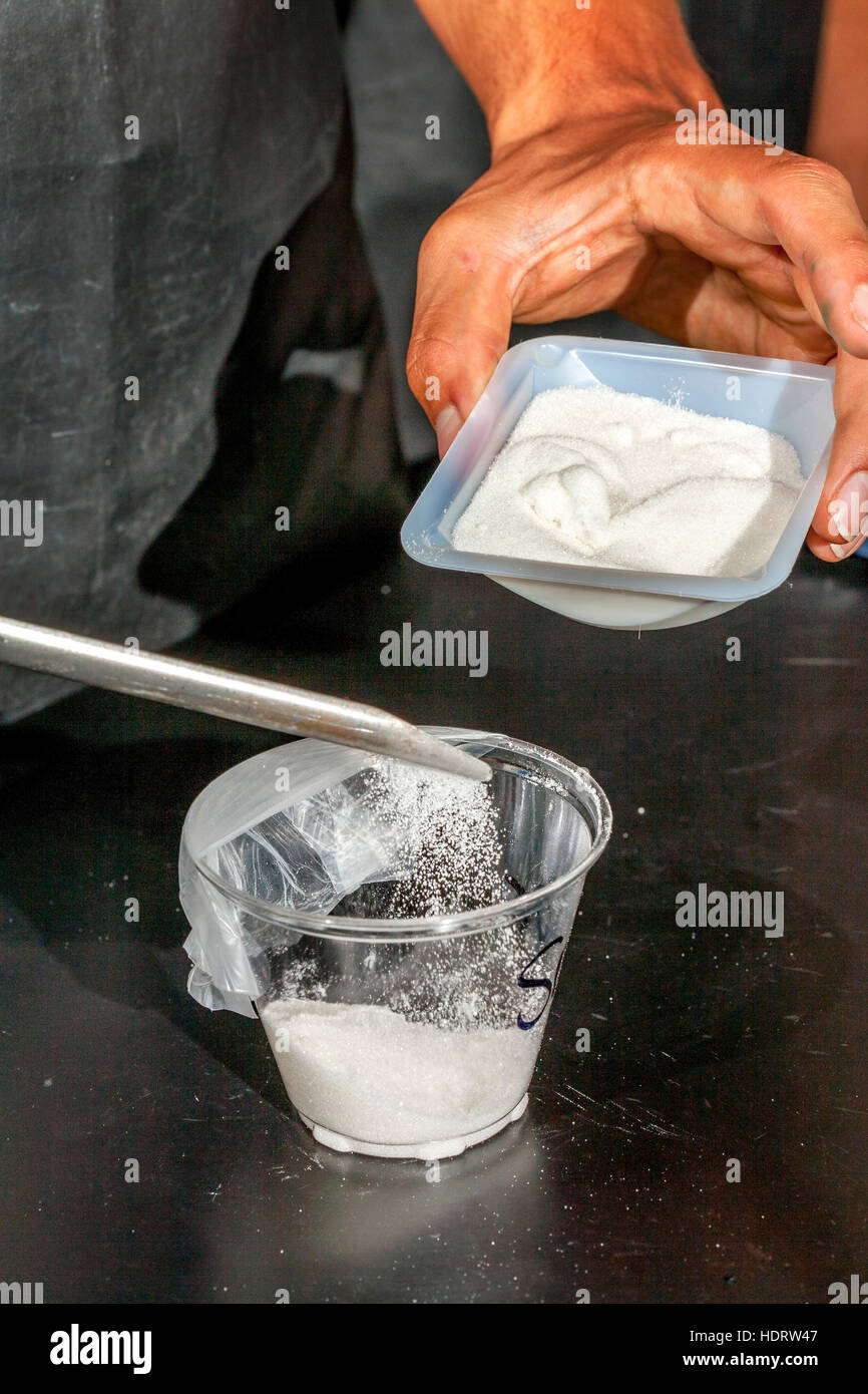Sodium Chloride powder is poured into a container for weighting in a