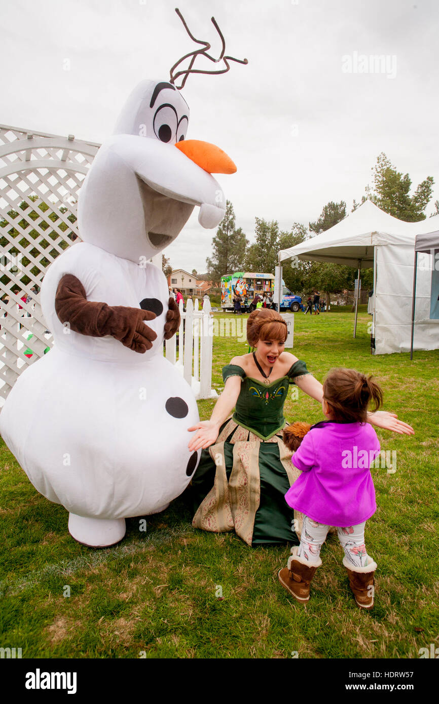 Along with a fanciful snowman assistant in costume, a Christmas fairy greets a little girl at a 'snowfest' with artificial snow in Lake Forest, CA. Stock Photo