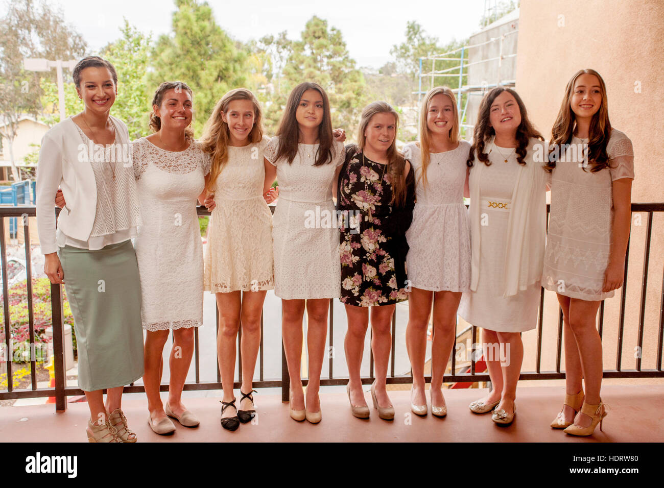 Wearing white formal dresses, multiracial teen girls  pose at a Laguna Niguel, CA, Catholic church before their Confirmation mass. Stock Photo