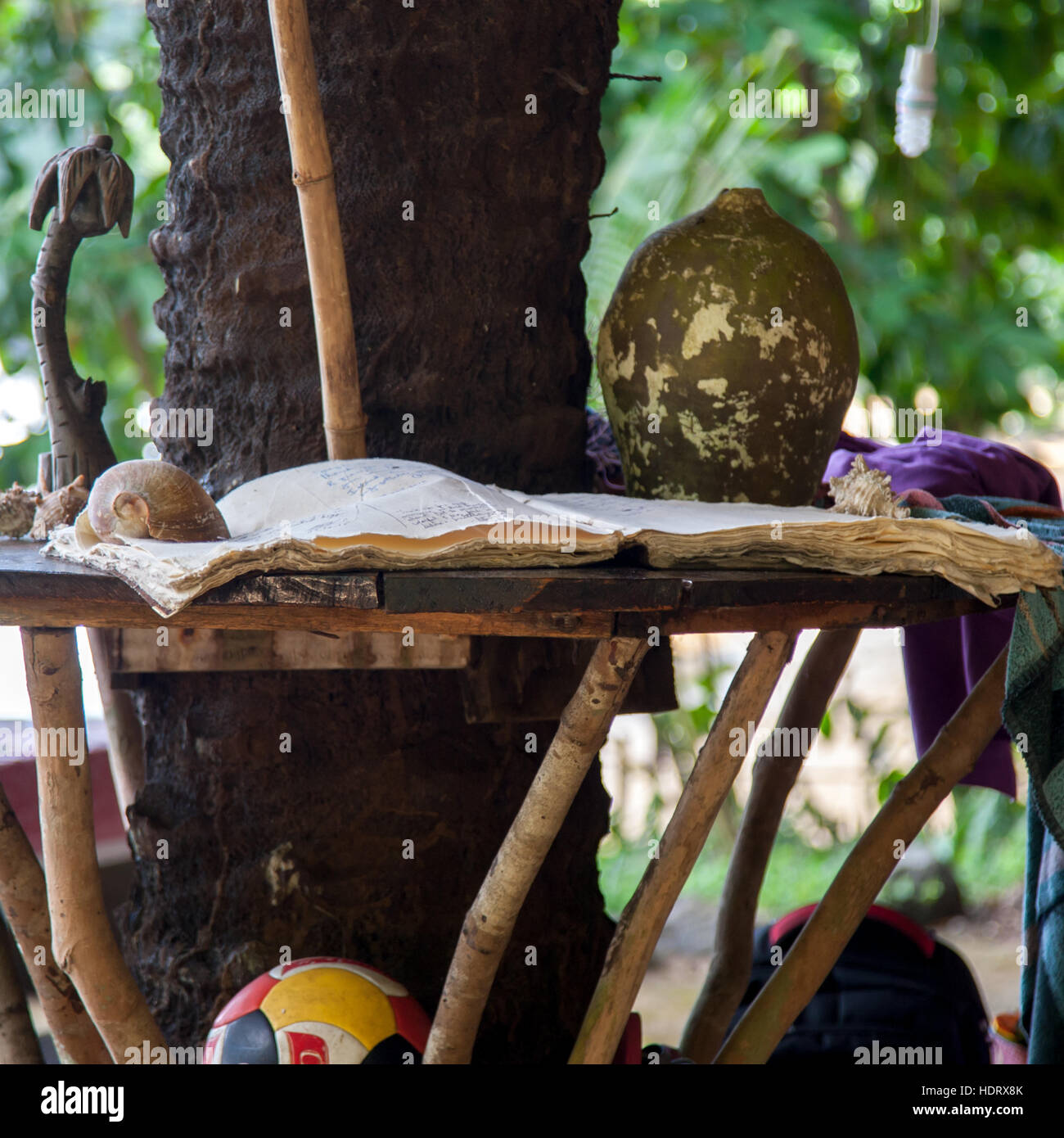 A painted dried gourd and carved palm-tree figures stand beside the guestbook on the table under the palm tree at the Banana Island Resort, Sierra Leone. Stock Photo