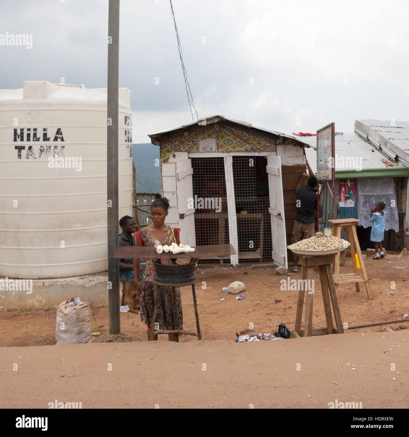 Mobile shop offering cassava roots and peanuts next to a huge tank of Drinking Water Stock Photo