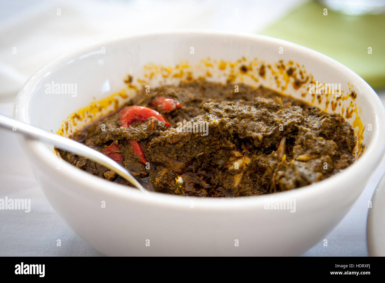 Cassava leafs are a common dish in Sierra Leone. In consistency, the popular spicy cassava sauce resembles pureed spinach. Depicted is a restaurant serving. In Sierra Leone, households usually eat together from one bowl Stock Photo