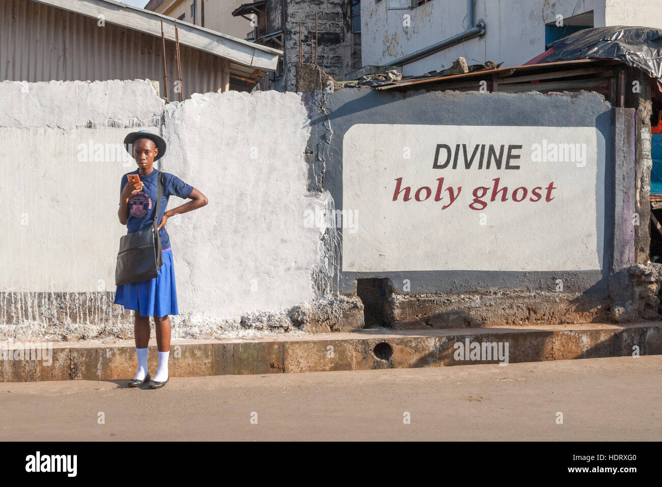 "Divine holy ghost" - Student standing in front of religious inscription in Sierra Leone Stock Photo