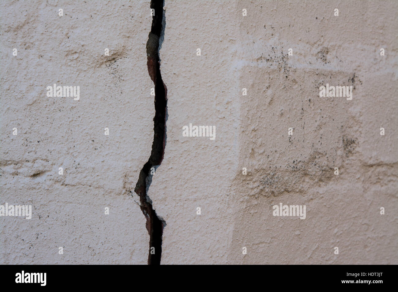 A large vertical crack in a painted brick wall Stock Photo