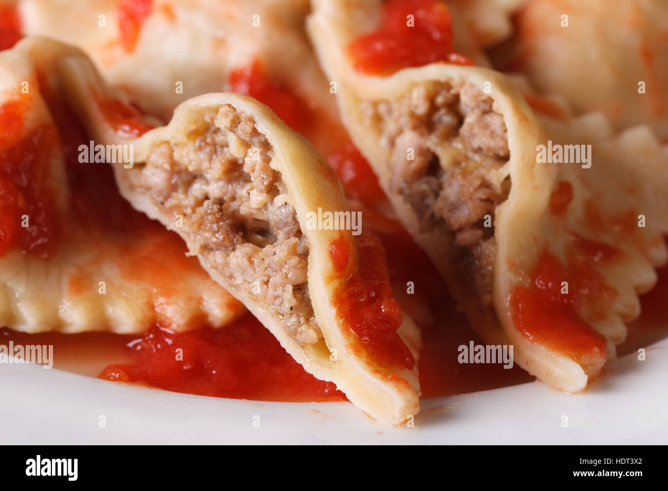Ravioli stuffed with meat in tomato sauce on a plate macro. Horizontal Stock Photo