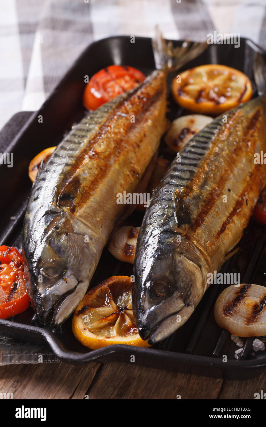 sea fish grilled mackerel and vegetables on the grill pan closeup. Vertical Stock Photo