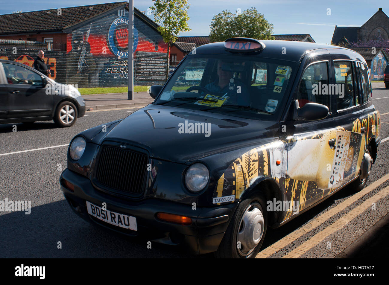 Belfast Black Taxi tours in front of one of the loyalist murals at the bottom of the Newtownards Road in East Belfast, Northern Ireland, UK. U.F.F. Mu Stock Photo
