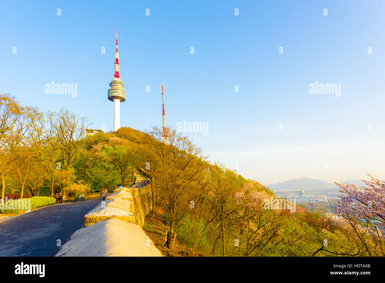 Footpath and old city wall form leading lines to peak of Namsan mountain's N Seoul Tower on a cloudless, clear spring day Stock Photo