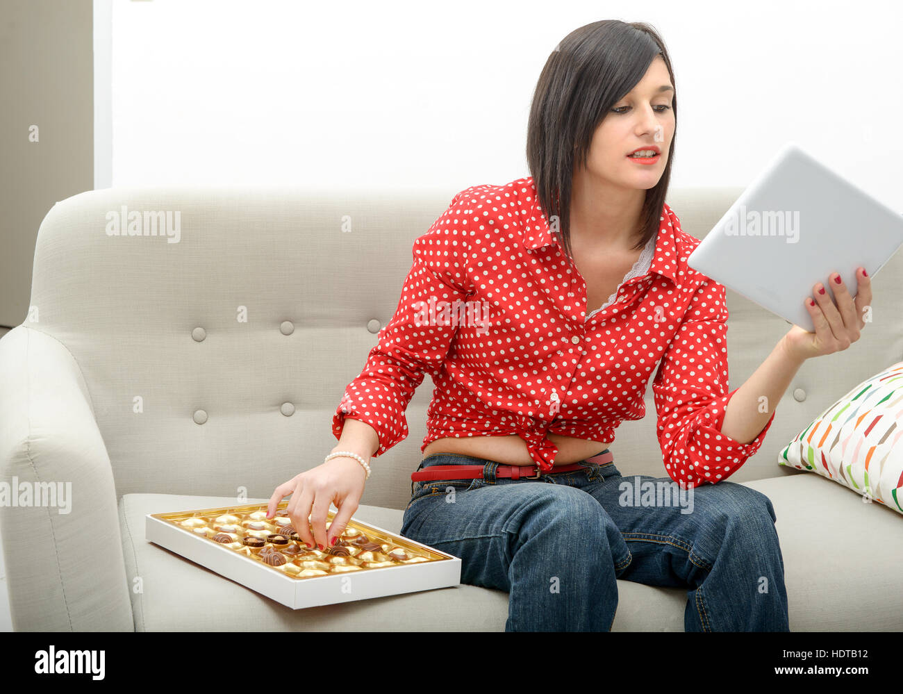 Young Brunette Eats Chocolate On Her Sofa Stock Photo 128998606