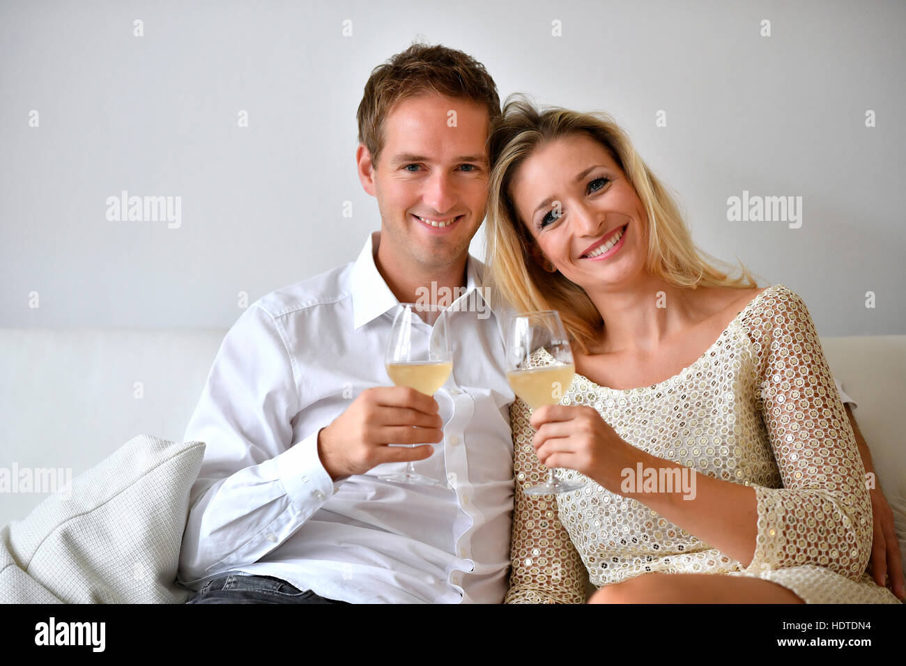 Man, woman, couple on sofa, in love, wine, glass, looking at camera Stock Photo