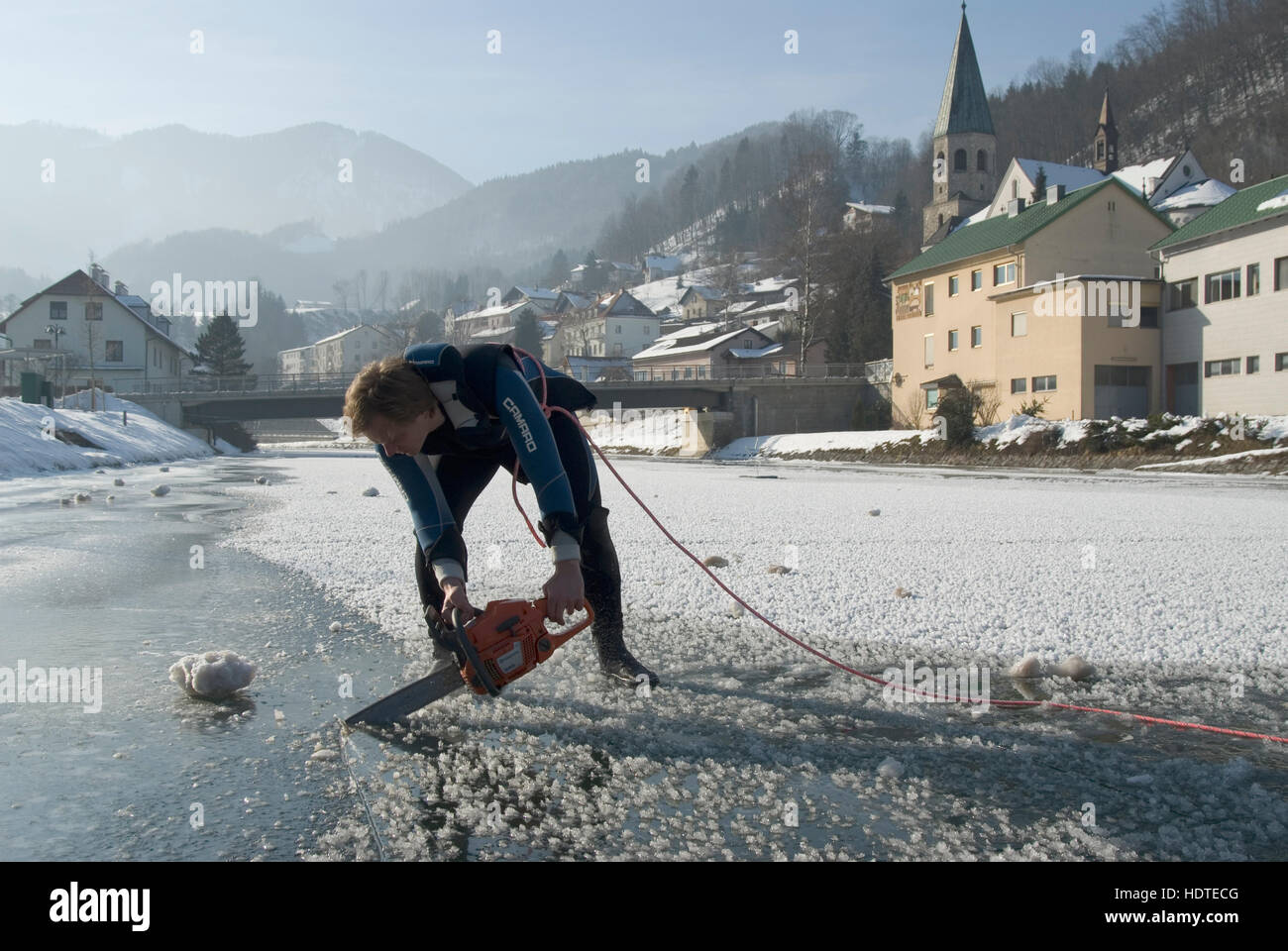 Using a chainsaw to cut a hole into the frozen surface for ice diving