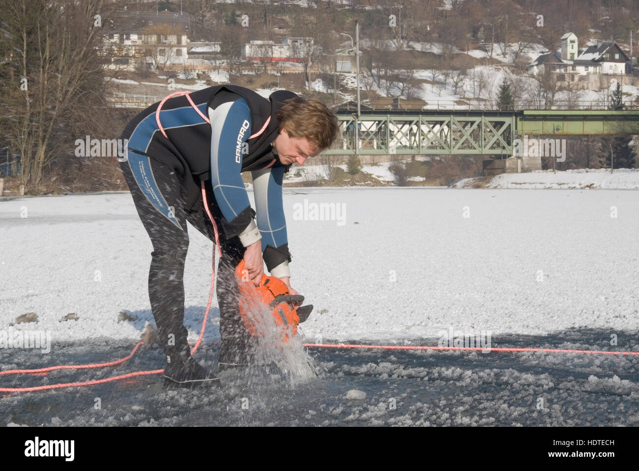 Using a chainsaw to cut a hole into the frozen surface for ice diving