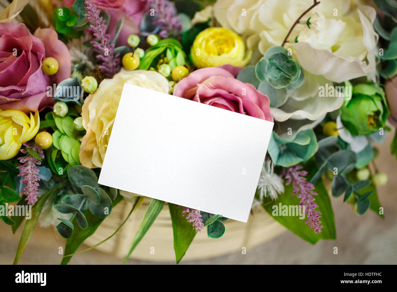 flowers in basket on the light wooden background. Space for text. Stock Photo