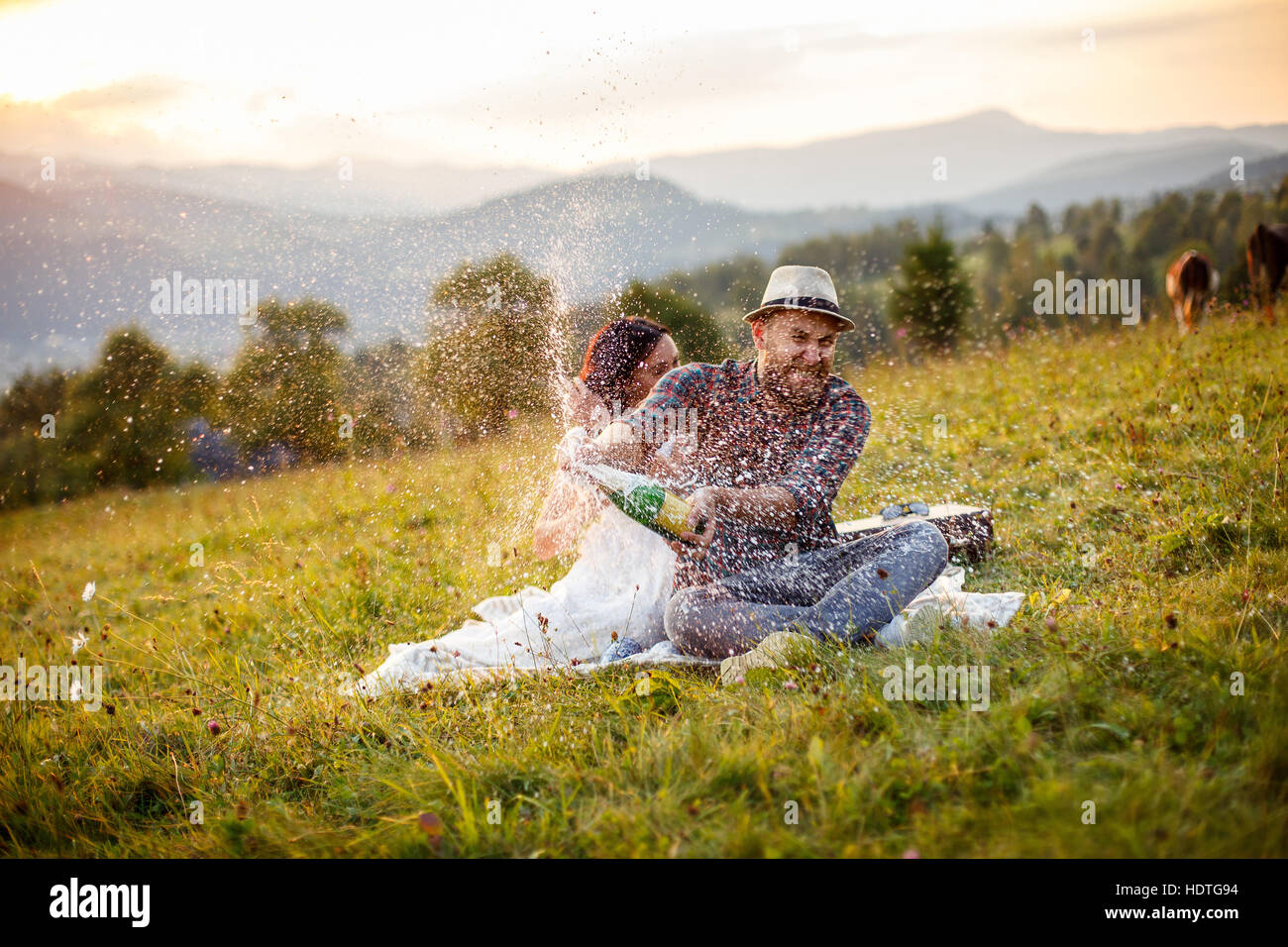 loving couple sitting on plaid in field. background mountains. Stock Photo