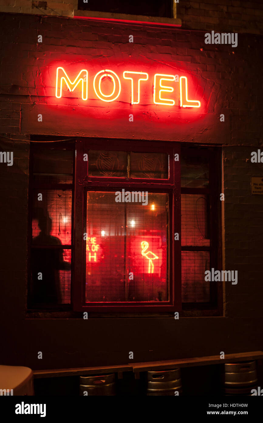 Shadow and neon flamingo through the window, under a neon motel sign. Reminiscent of the movie Psycho, or seedy 1970's downtown, New York, L.A Stock Photo